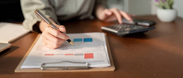 istock Businesswoman using laptop computer and working at office with calculator document on desk, doing planning analyzing the financial report, business plan investment, finance analysis concept 2111002356
