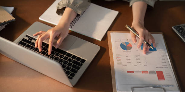 istock Businesswoman using laptop computer and working at office with calculator document on desk, doing planning analyzing the financial report, business plan investment, finance analysis concept 2111002872