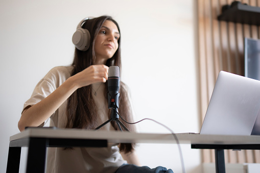 Young Woman live Recording Talk Show Episode on the radio With Microphone and Laptop in the studio