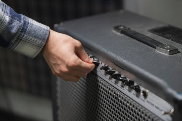 istock Guitarist Fine-Tunes Amplifier Settings Before a Performance in a Backstage Area 2111019384