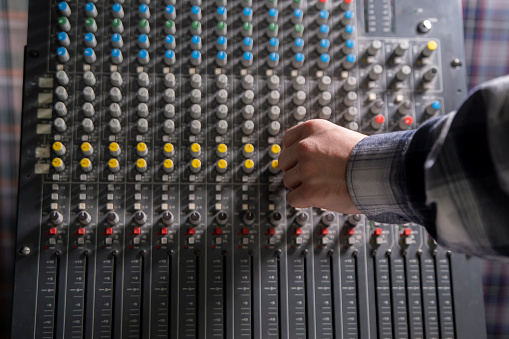 Close-Up of a Hand Adjusting the Controls on a Music Mixer Console in a Studio