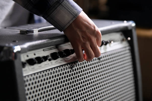 istock Guitarist Fine-Tunes Amplifier Settings Before a Performance in a Backstage Area 2111019915