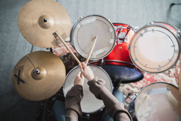 drummers hands holding sticks mid-performance on a drum set - toms стоковые фото и изображения