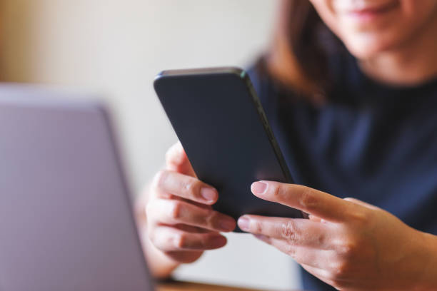 istock Closeup image of a young woman using smart phone and laptop computer 2111041088