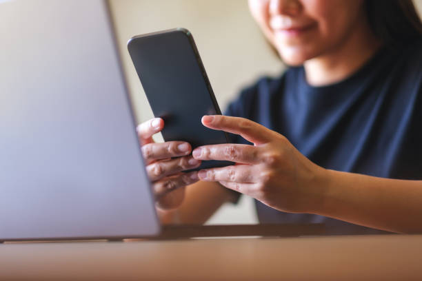 istock Closeup image of a young woman using smart phone and laptop computer 2111041108