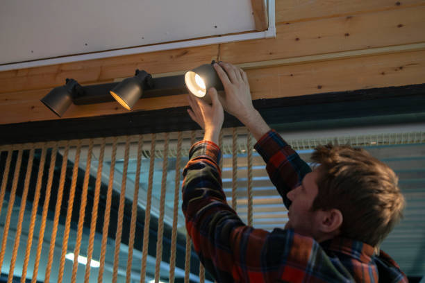 istock Man Changing a Burnt-Out Light Bulb on a spot light construction in an Office Ceiling Fixture 2111070977