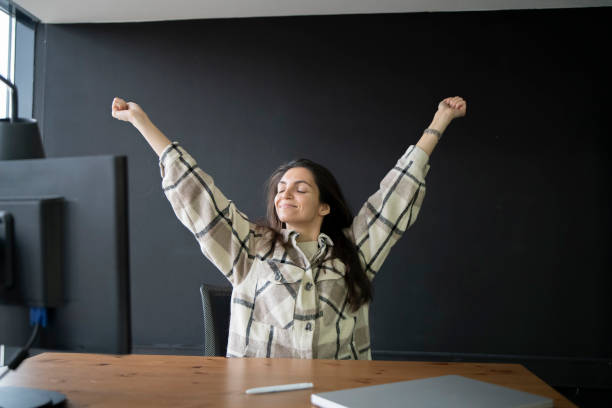 istock Woman Stretching Arms Upward During a Break in a Modern Office Workspace 2111071551