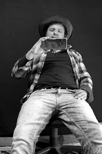 seated man taking a selfie with a mobile phone, black and white photo