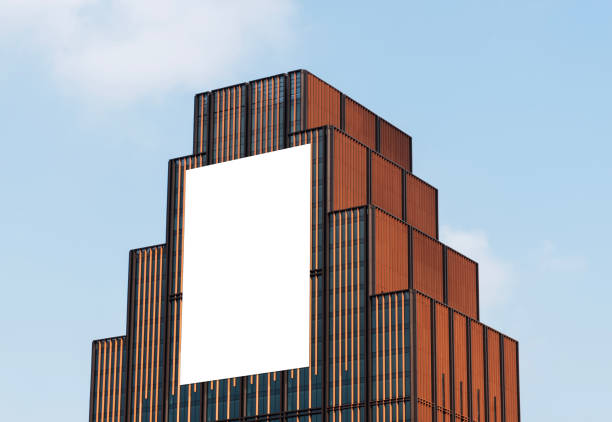 Mock up white vertical large LED display billboard on tower building with blue sky background .clipping path for mockup