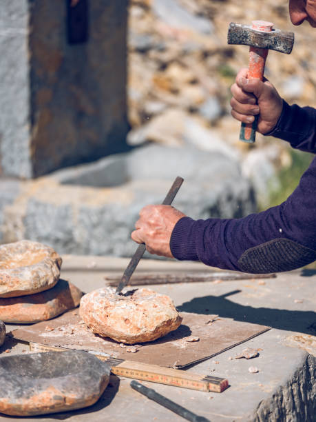 istock Crop artisan shaping stone with chisel and hammer 2111117525