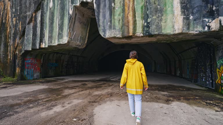 SLO MO Rear View of Young Female Tourist Walking Towards Abandoned Underground Zeljava Air Base in Croatia