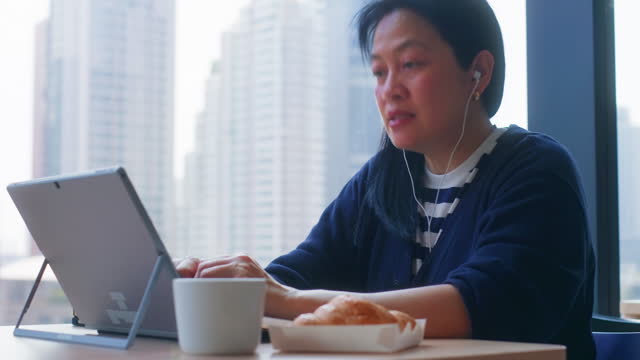 asian woman using laptop video confernce with team at cafe working remotely