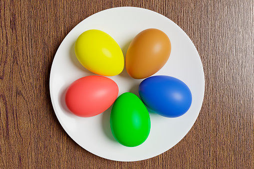 Painted Easter eggs lie on a white ceramic plate.