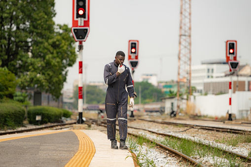 Portrait of a railway engineer, Check the tracks and use the walkie talkie to communicate with colleagues. While standing on the train station platform