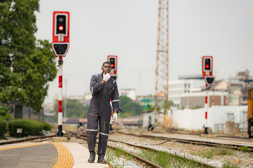 Portrait of a railway engineer, Check the tracks and use the walkie talkie to communicate with colleagues. While standing on the train station platform