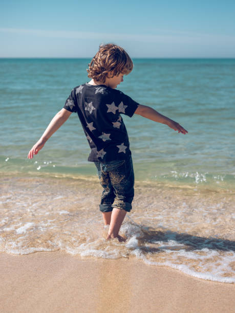 istock Boy walking in sea water 2111189131