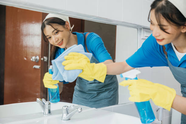 istock Maid with rubber gloves wipes bathroom mirror ensuring shiny reflection with a rag. Hotel service highlights professional cleaning ensuring purity and hygiene in modern settings. Maid cleaning at home 2111219054