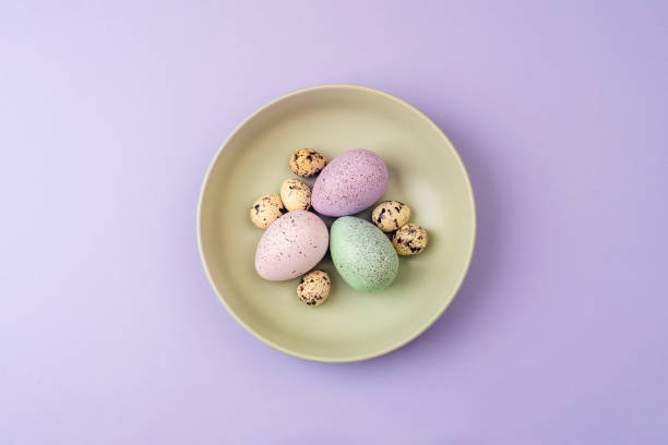 istock Easter table with green plate and Easter eggs on purple background. Top view, flat lay 2111244658