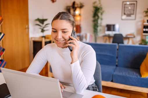 Beautiful woman enjoying while shopping online at home sitting on kitchen table