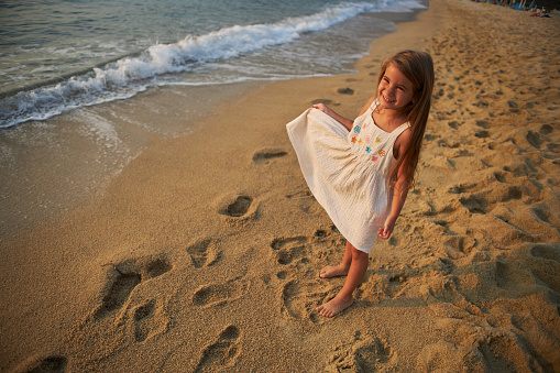 Little girl enjoying a tropical paradise beach during sunset.