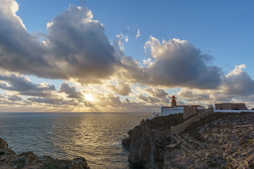 Sunset at lighthouse of Cabo de Sao Vicente with sunlight shining through clouds, Sagres, Algarve, Portugal