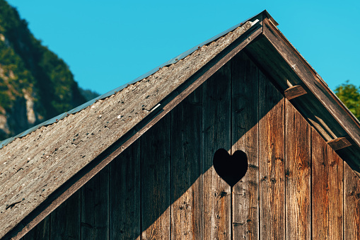 Heart-shaped pigeon hole on wooden farm shed, detail from Bohinj region in Slovenia, selective focus