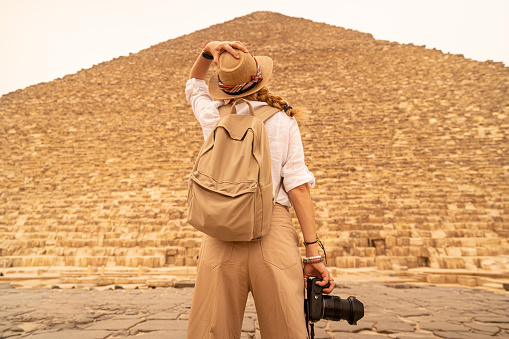 Female photographer in vacation standing with photo camera in front of the great pyramids. Egypt, Cairo - Giza