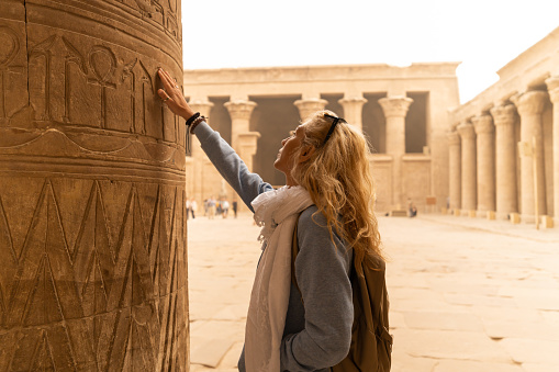 Female tourist touching columns of the temple of Horus in Edfu, Egypt. Esna and Aswan in Egypt.