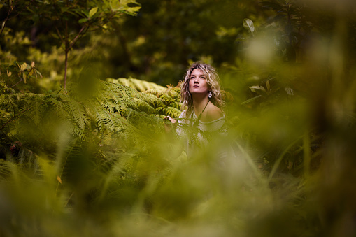 Young woman day dreaming while being among greenery in the forest.