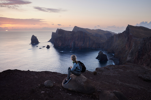 Relaxed female backpacker looking at sea view on Ponta De Sao Lourenco at twilight. Copy space.