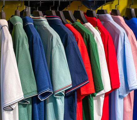 Colorful t-shirts hanging on hangers in clothing store