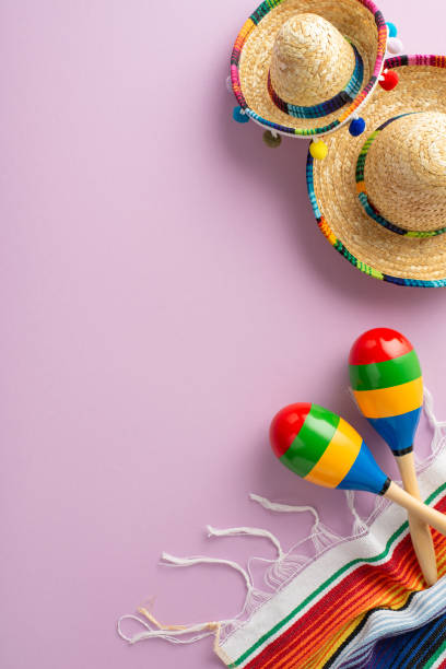 istock Celebratory Cinco de Mayo composition from vertical top view, showcasing thematic decorations like sombreros, maracas, a lively serape, all arranged on a gentle purple surface 2111423816