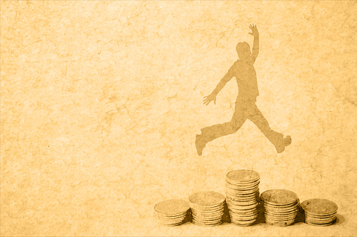 On young man silhouette jumping with joy over Heaps of traced money or pile of old faded distressed golden coloured currency coins arranged as set or stacks of abundant money over beige coloured vintage classic style cracked horizontal vector background