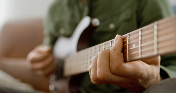 Close-up of man hand's playing guitar of music lesson at home.