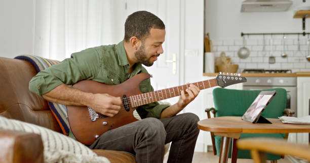istock Man learning to play guitar with tablet 2111441712
