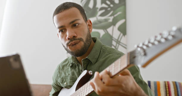 istock Man learning to play guitar with tablet 2111441722