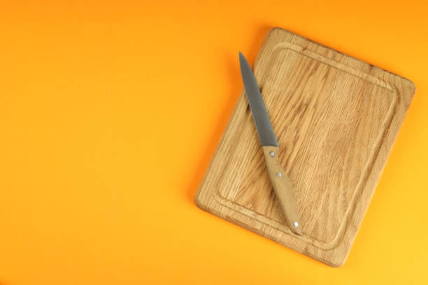 istock Cutting board with knife on orange background 2111442261
