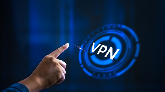 A hand pointing to a blue circle with the word VPN written in white. Concept of a person accessing the internet through a virtual private network