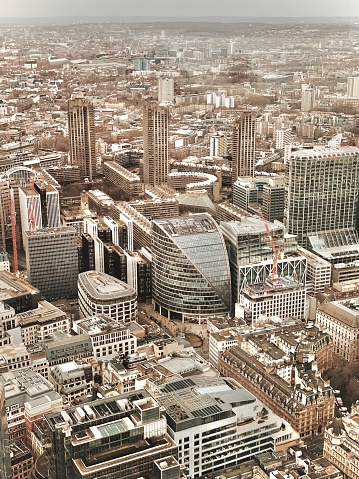 London City Skyline, the Moor House building, and the Shakespeare Tower, Cromwell Tower, and Lauderdale Tower in London. 

This aerial photograph shows a view of London from above. The photo presents the urban landscape of the city, including famous landmarks: Some features that can be seen are the Shakespeare Tower, Cromwell Tower, and Lauderdale Tower, which are part of the iconic Barbican Estate. These tall residential towers were built in the Brutalist architectural style. Also visible are the Golden Lane Estate and Barbican Centre Arts Complex.