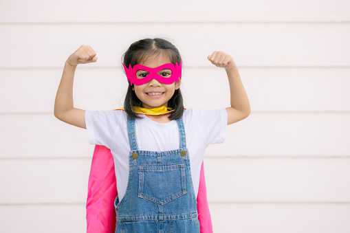 A funny little girl wearing a Superhero costume. Superhero concept.