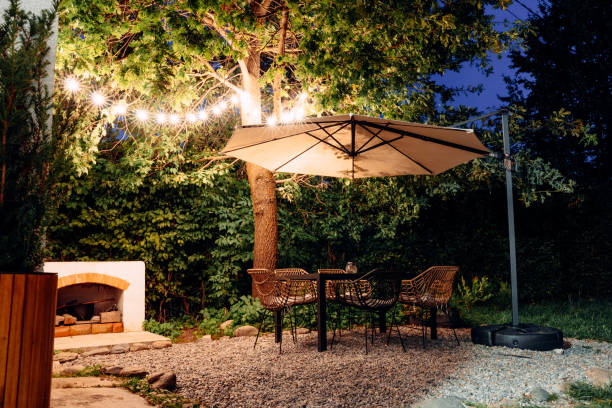 istock Outdoor patio with table, chairs, and umbrella illuminated by string lights 2111523296