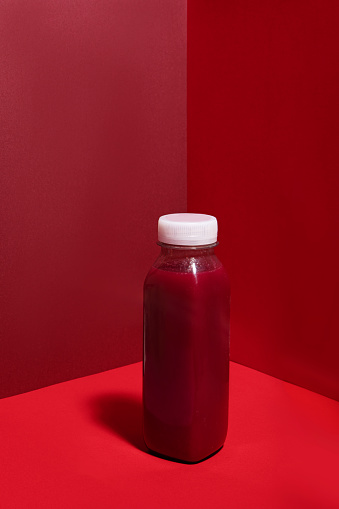 A plastic bottle of healthy red juice on a colourful background as an example of sustainable recycling