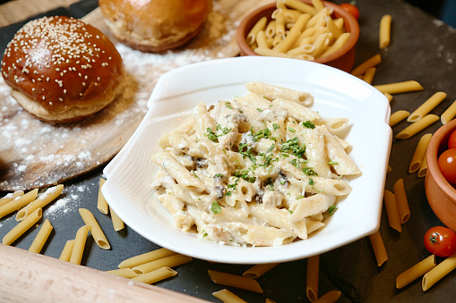 A plate of pasta and a hamburger arranged on a table, showcasing a delicious meal.