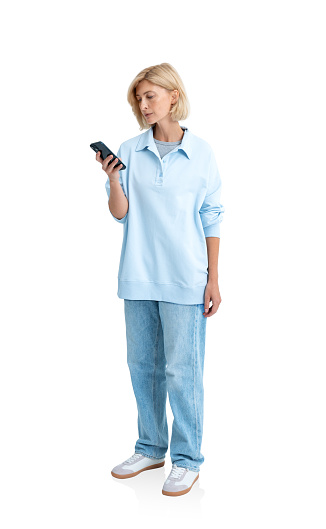 Young serious woman using phone, full length looking at smartphone isolated over white background. Concept of online communication, social media and mobile conversation