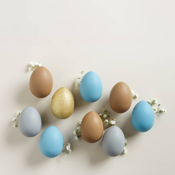 istock Easter Eggs pattern with White Gypsophila flowers on Light beige Background. Dyed colorful eggs in pastel colors, spring holiday photo, tender soft hues, flatly of celebration food and white blooms 2111537120