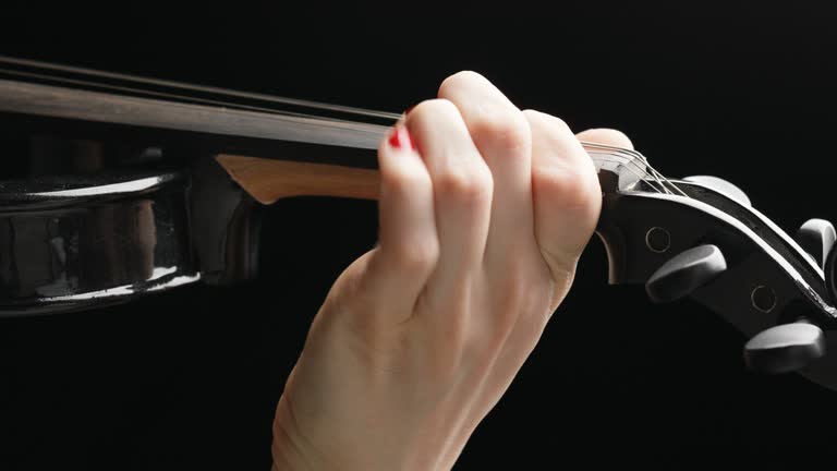 Red-nailed hand plays electric violin, black background