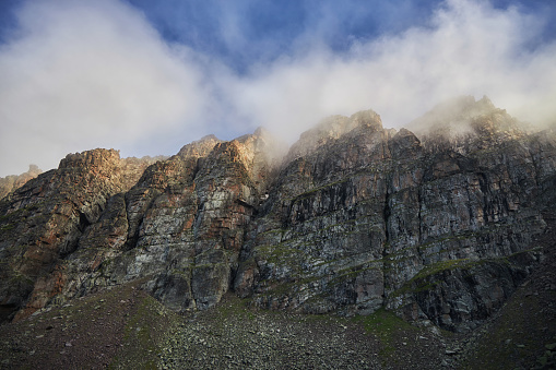 Mist wraps the rugged peaks of a mountain range, with the morning sun illuminating the scene