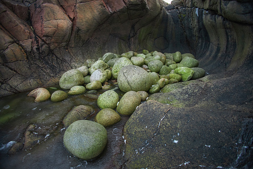 Dragon eggs rocks bask in sunlight within a tranquil rock pool, showcasing natures textures. Teriberka, Russia