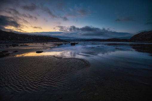 Twilight sky with clouds over a serene coastal setting, reflected in calm tidal pools