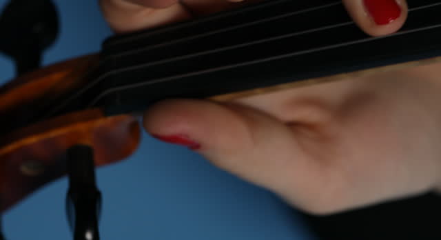 Red nails and violin strings against blue background